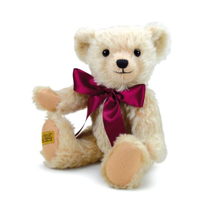 Henley's rich cream mohair has been carefully worked with pinky-beige wool felt, both complemented by an opulent burgundy satin bow. This adorable teddy bear's beaming smile is highlighted by a short-trimmed muzzle, giving him a friendly personality that all will fall in love with.  Each Merrythought soft toy in the Traditional Collection is presented with a drawstring bag, to help keep your new companion clean and dust-free.