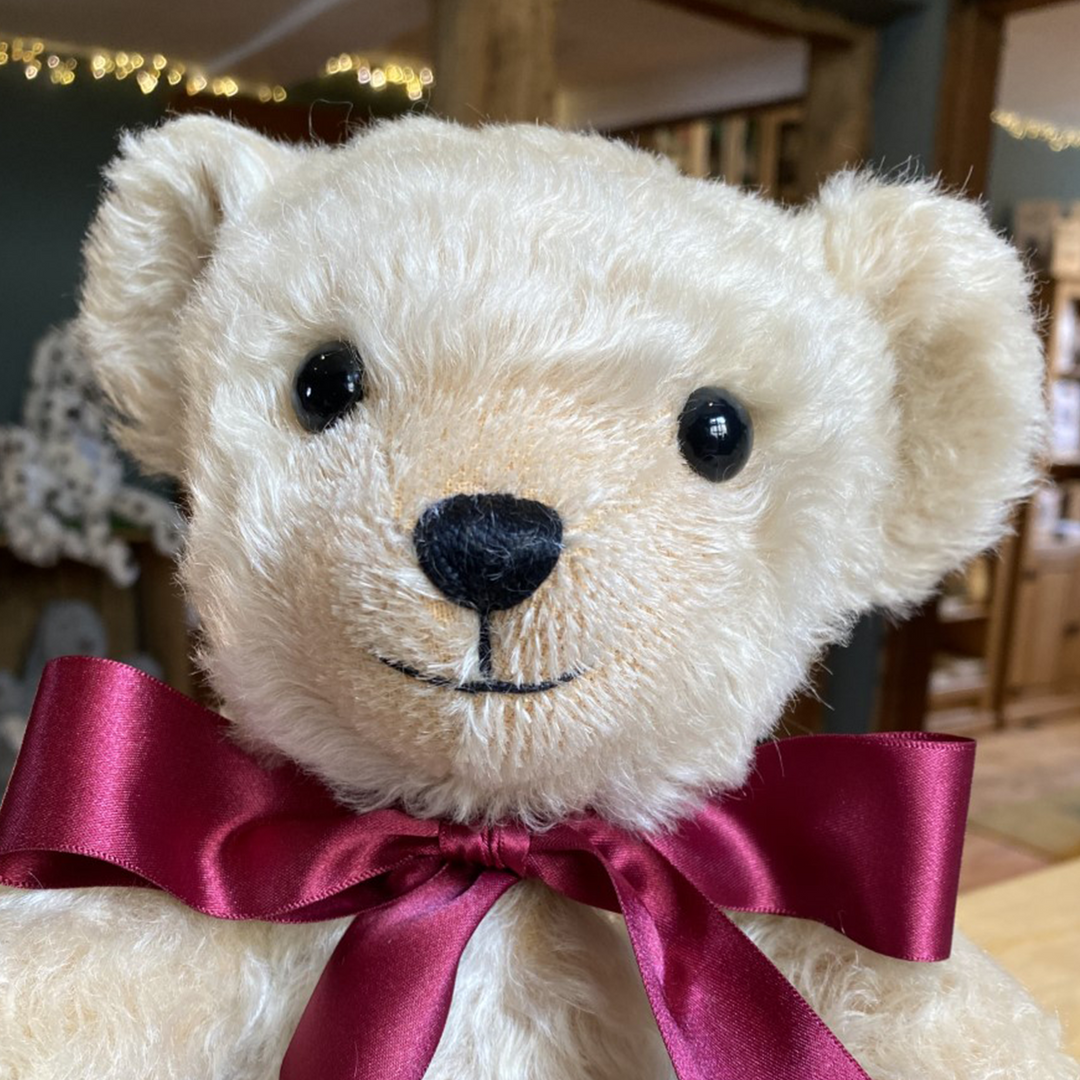 Henley's rich cream mohair has been carefully worked with pinky-beige wool felt, both complemented by an opulent burgundy satin bow. This adorable teddy bear's beaming smile is highlighted by a short-trimmed muzzle, giving him a friendly personality that all will fall in love with.  Each Merrythought soft toy in the Traditional Collection is presented with a drawstring bag, to help keep your new companion clean and dust-free.