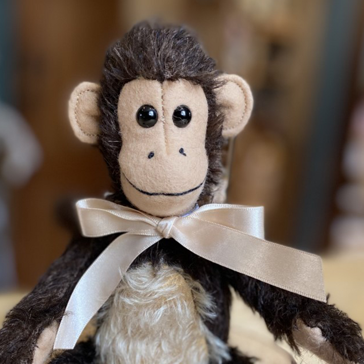 Milo's enchanting expression is sure to capture the hearts of everyone who meets him. His peachy-beige wool felt hands, feet and smiley face beautifully accompany dark-mahogany mohair, while an authentic curly monkey's tail truly brings his character to life.